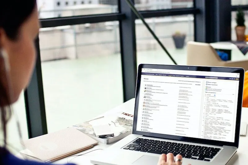 Ein Laptop in einem Büro, bedient von einer Frau mit Kopfhörern. Auf dem Bildschirm läuft CentralStationCRM.
